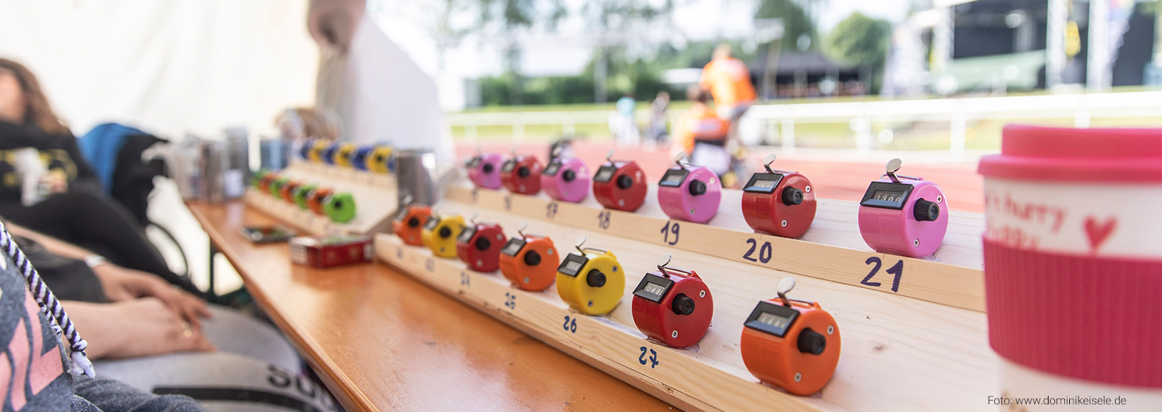 Fotografie: Eventorganisation für das 24h-Rollstuhlrennen – Zeitnahme und Rundenzählung Handzähler auf einem Tisch bei der Organisation des 24-Stunden-Rollstuhlrennens in Eislingen. Die farbigen Zählgeräte werden zur Erfassung von Runden und Ergebnissen während des inklusiven Sportevents eingesetzt.