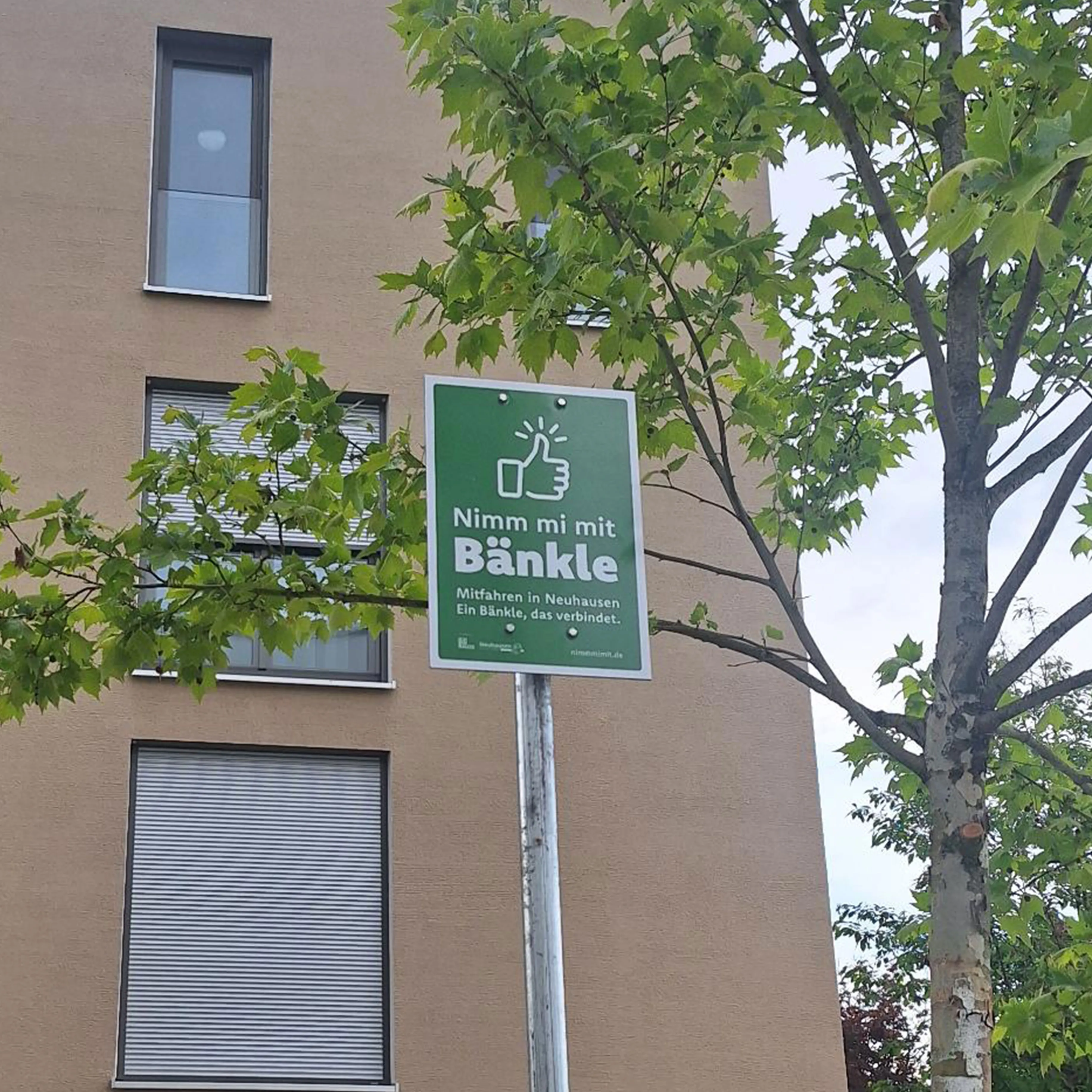 Schilderdesign für die Mitfahrbank-Initiative Nimm mi mit Bänkle in Neuhausen auf den Fildern Standortschild der Mitfahrinitiative „Nimm mi mit Bänkle“ in Neuhausen auf den Fildern. Das grüne Schild kennzeichnet eine Mitfahrbank und unterstützt nachhaltige Mobilität sowie nachbarschaftliche Hilfe im Ort.